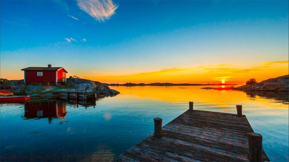 Swedish archipelago with numerous small islands, sailing yacht, sunset golden light, aerial view